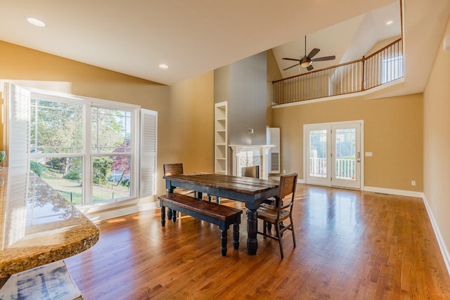 dining space with hardwood / wood-style floors, high vaulted ceiling, and ceiling fan