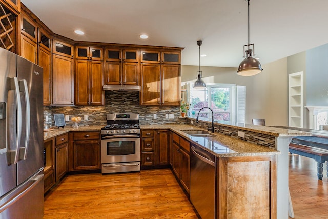 kitchen with hardwood / wood-style floors, sink, appliances with stainless steel finishes, and pendant lighting