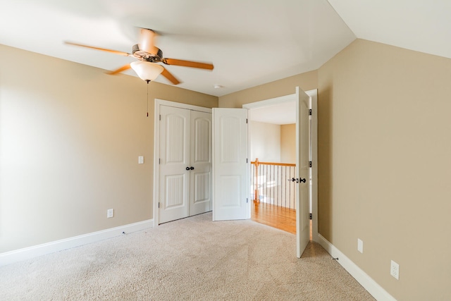 unfurnished bedroom featuring a closet, ceiling fan, vaulted ceiling, and light colored carpet