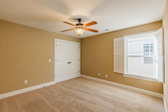 unfurnished bedroom featuring light carpet, a closet, and ceiling fan