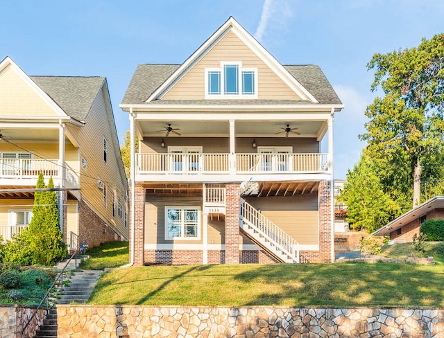 rear view of house featuring ceiling fan, a lawn, and a balcony