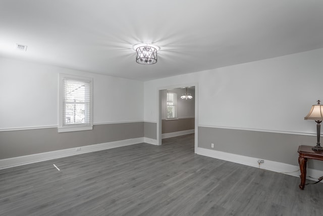 unfurnished room with dark hardwood / wood-style flooring and an inviting chandelier