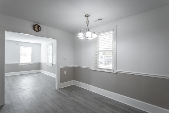 empty room with dark hardwood / wood-style flooring and an inviting chandelier