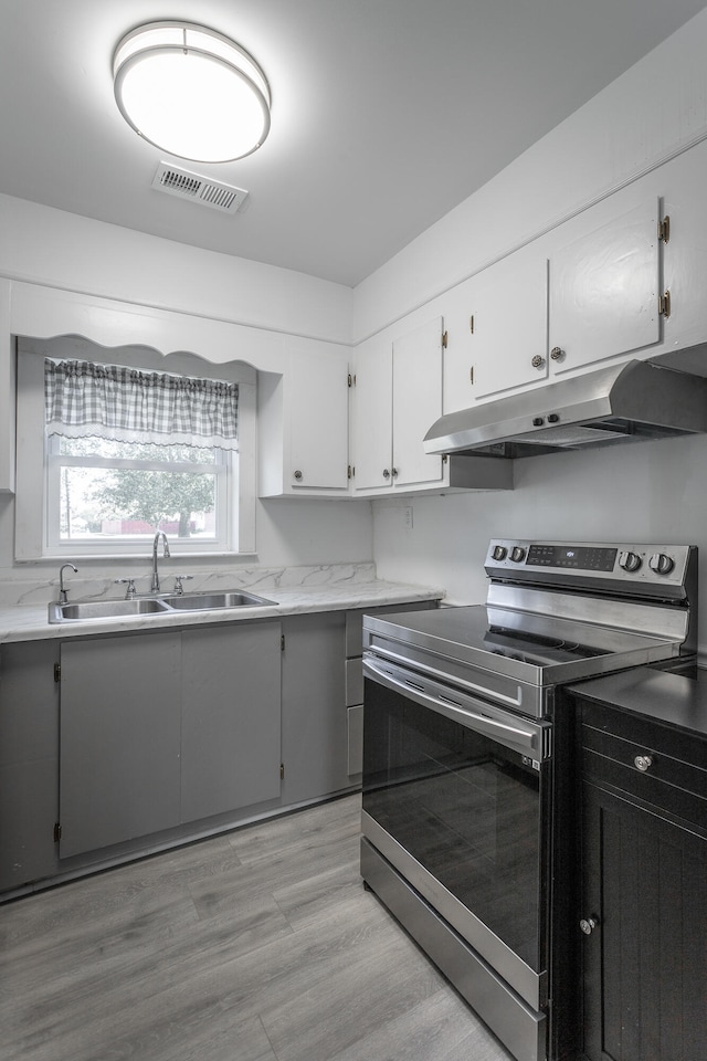 kitchen featuring electric range, white cabinetry, sink, and light hardwood / wood-style flooring