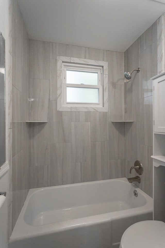 bathroom featuring toilet and tiled shower / bath