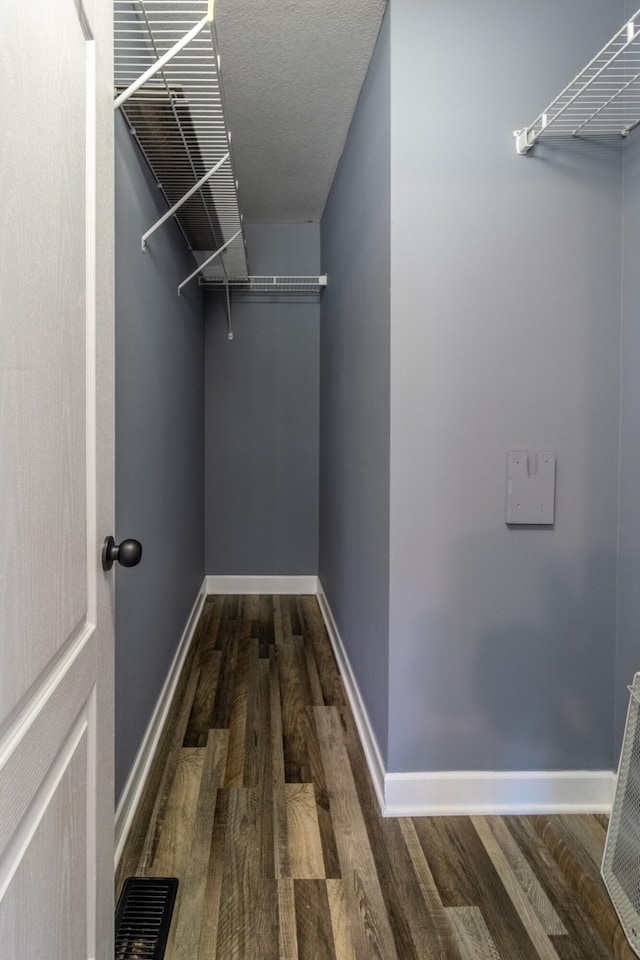 walk in closet with dark hardwood / wood-style flooring