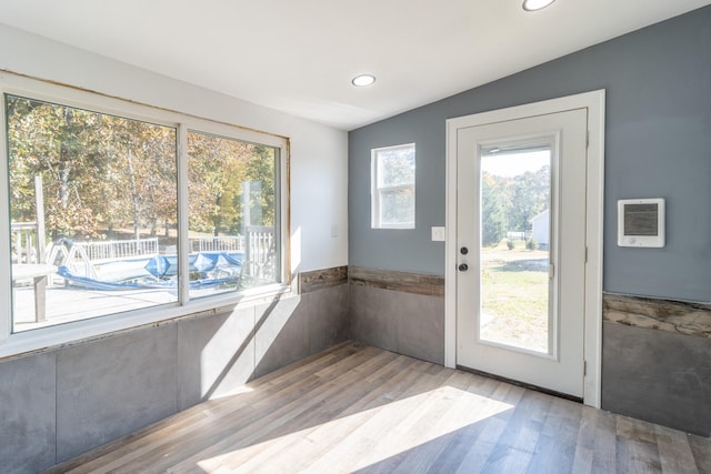 doorway with heating unit, lofted ceiling, and light hardwood / wood-style flooring