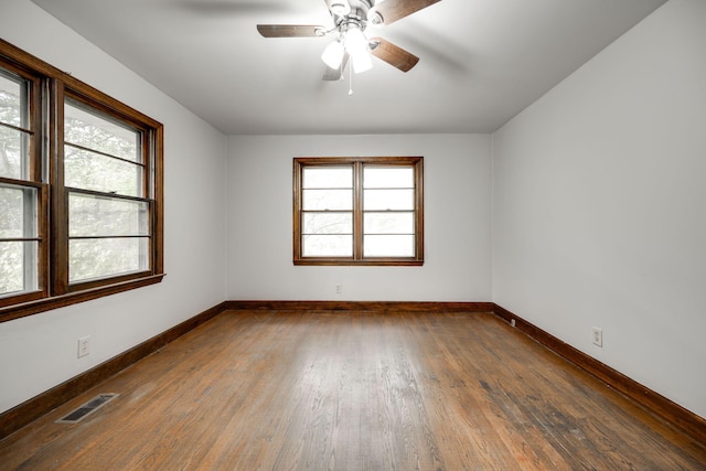 empty room with plenty of natural light, dark hardwood / wood-style floors, and ceiling fan