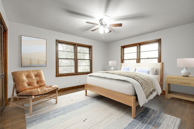 bedroom with a closet, multiple windows, wood-type flooring, and ceiling fan