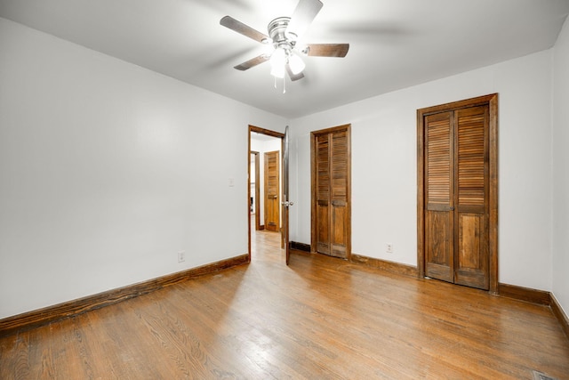 unfurnished bedroom with multiple closets, light hardwood / wood-style floors, and ceiling fan