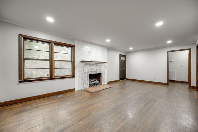 unfurnished living room with a brick fireplace, wood-type flooring, and ornamental molding