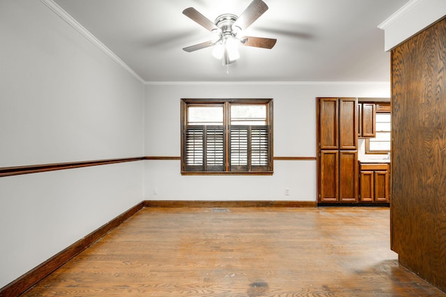 spare room featuring ceiling fan, light wood-type flooring, and crown molding