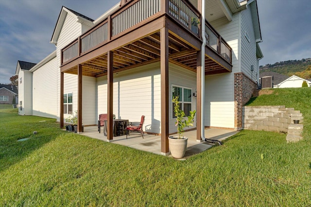 rear view of house featuring a patio, a deck, and a lawn