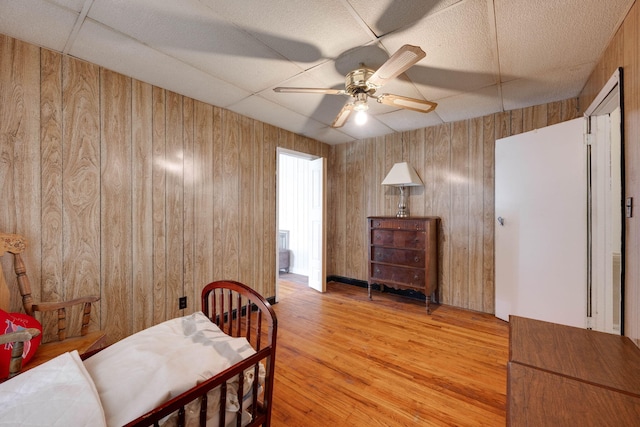 bedroom featuring ceiling fan, wood walls, and light wood-type flooring