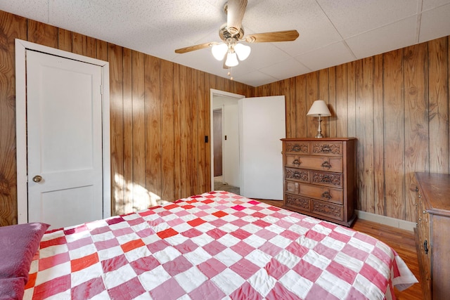 bedroom with wood walls, a closet, and ceiling fan