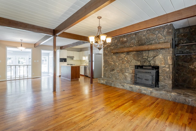 unfurnished living room with light hardwood / wood-style floors, a notable chandelier, and beamed ceiling