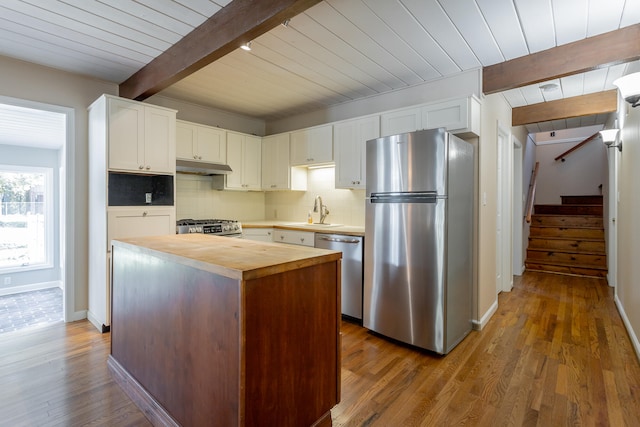 kitchen featuring dark hardwood / wood-style flooring, white cabinetry, beamed ceiling, stainless steel appliances, and a center island