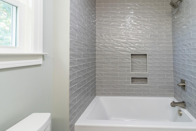 bathroom featuring tiled shower / bath and toilet