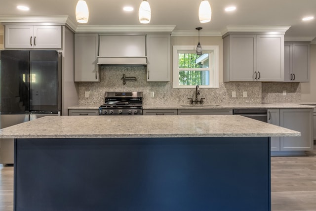 kitchen featuring crown molding, sink, decorative light fixtures, light wood-type flooring, and appliances with stainless steel finishes