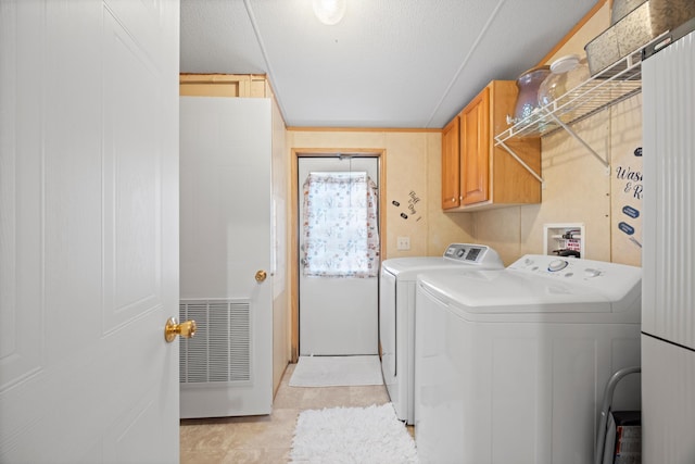 washroom with cabinets, washing machine and clothes dryer, light tile patterned floors, and a textured ceiling