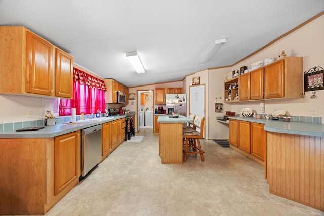 kitchen featuring a kitchen bar, vaulted ceiling, sink, a kitchen island, and appliances with stainless steel finishes