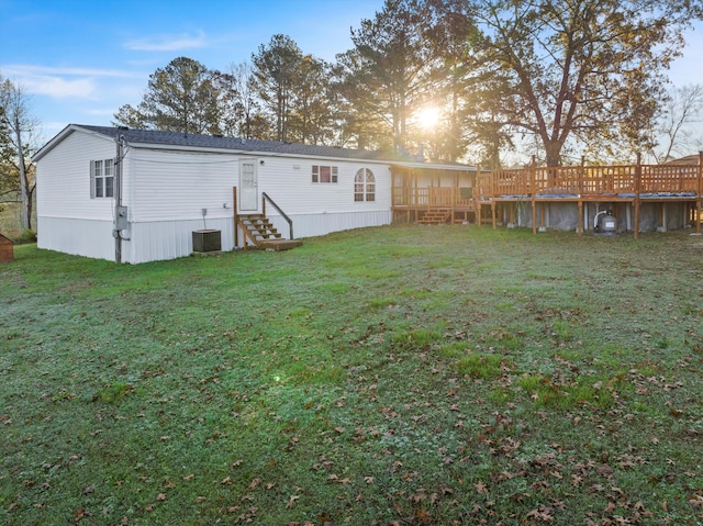 back house at dusk featuring cooling unit, a sunroom, and a yard