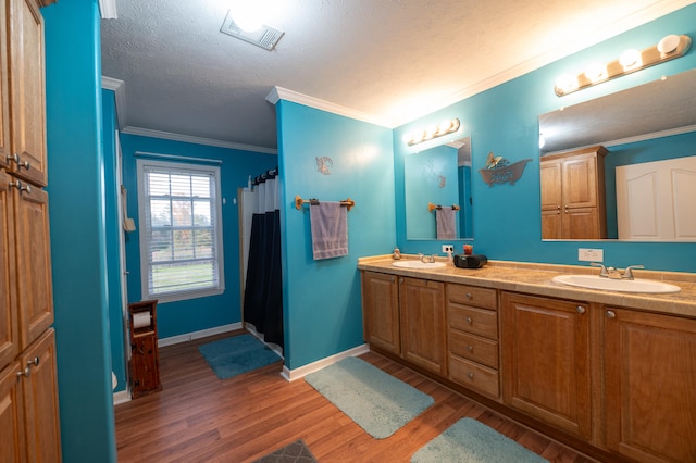 bathroom featuring ornamental molding, wood-type flooring, a textured ceiling, and vanity