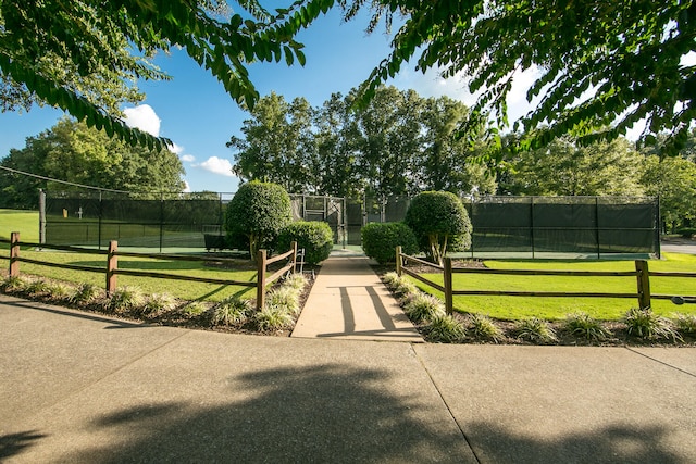 view of community featuring a lawn and tennis court