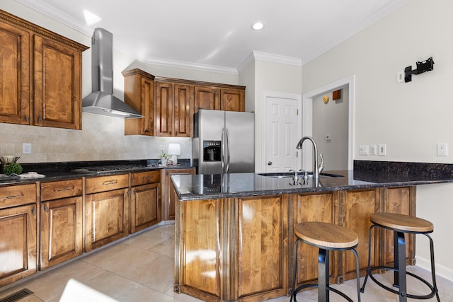 kitchen featuring stainless steel fridge with ice dispenser, sink, wall chimney exhaust hood, and dark stone countertops