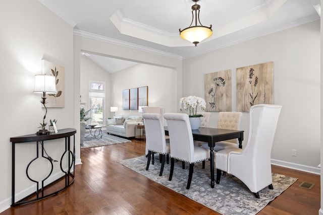 dining space featuring a raised ceiling, dark hardwood / wood-style flooring, and ornamental molding