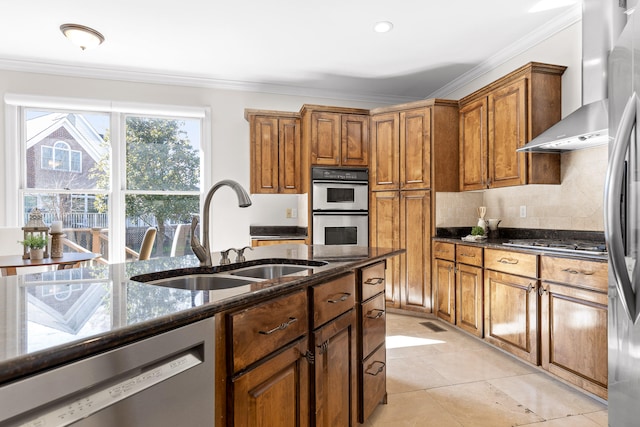 kitchen with sink, wall chimney exhaust hood, stainless steel appliances, dark stone counters, and ornamental molding