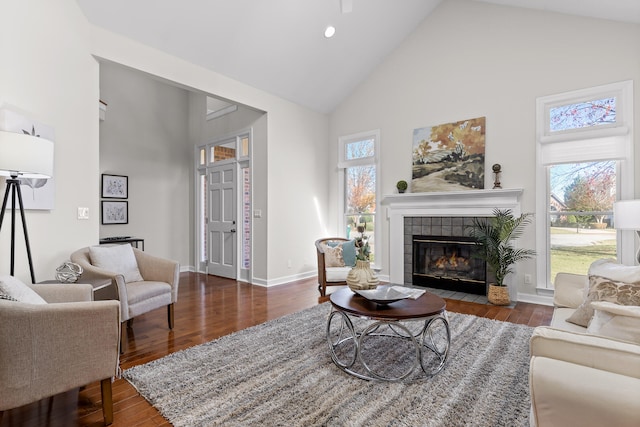 living room with a tiled fireplace, hardwood / wood-style floors, and high vaulted ceiling