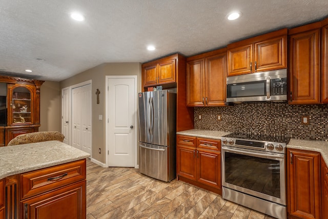 kitchen with backsplash, a textured ceiling, light hardwood / wood-style floors, and stainless steel appliances