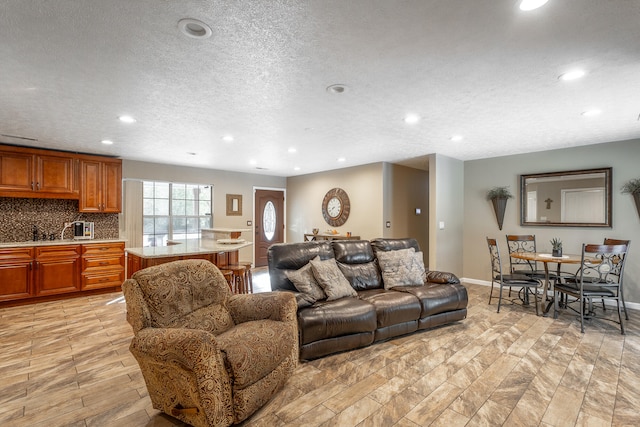 living room featuring light wood-type flooring, a textured ceiling, and sink