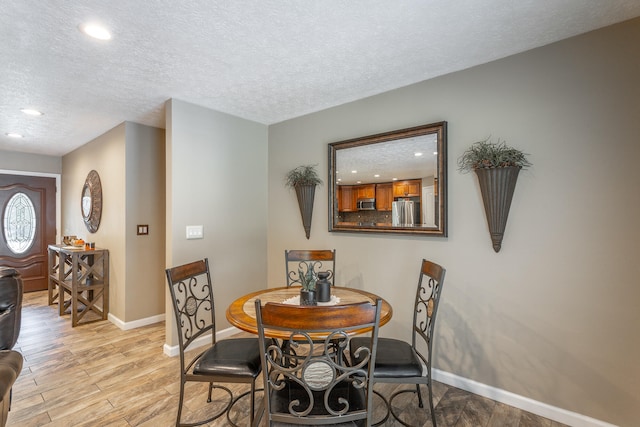 dining space featuring a textured ceiling and light hardwood / wood-style flooring