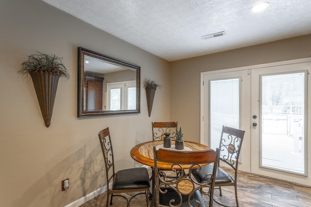 dining area with a textured ceiling, french doors, and hardwood / wood-style flooring