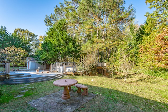 view of yard featuring a wooden deck, a patio, and a shed