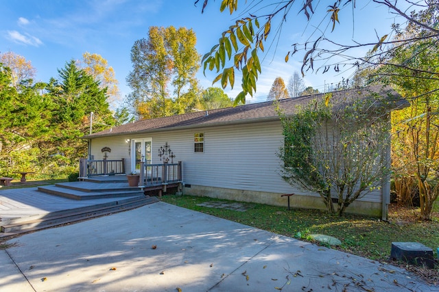 rear view of house with a wooden deck and a patio area