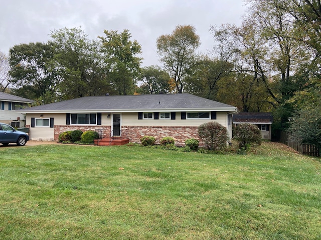 ranch-style home featuring a front lawn and a storage shed