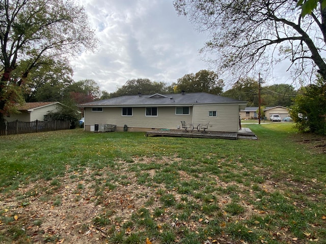 back of property featuring a wooden deck and a lawn