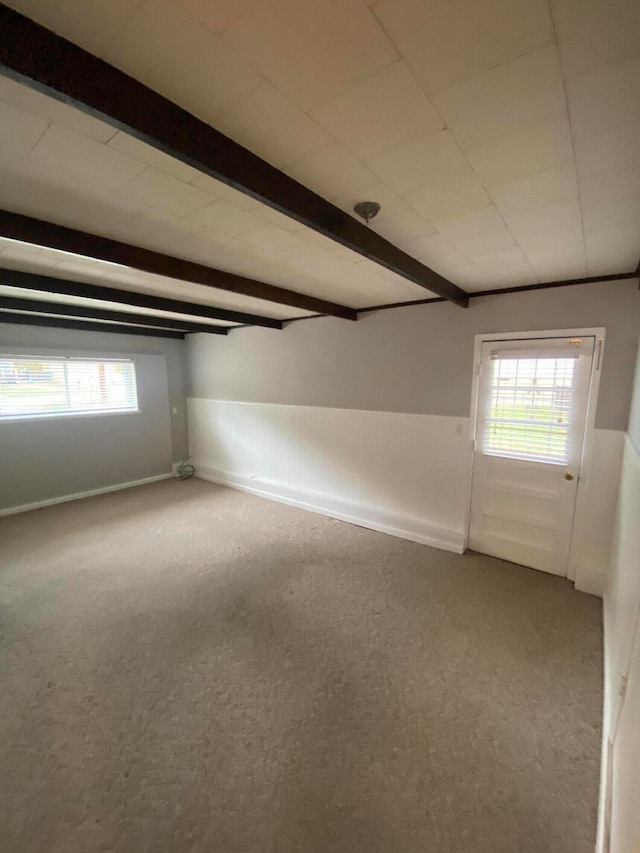 unfurnished room featuring beamed ceiling and carpet floors