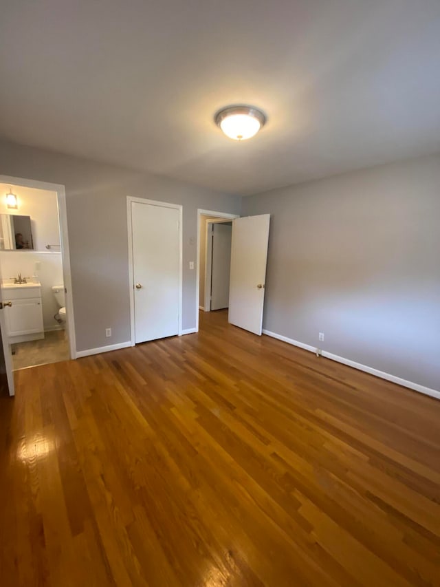 unfurnished bedroom with hardwood / wood-style floors and ensuite bathroom