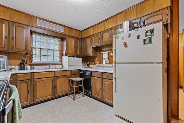 kitchen with a textured ceiling, wooden walls, sink, and white appliances