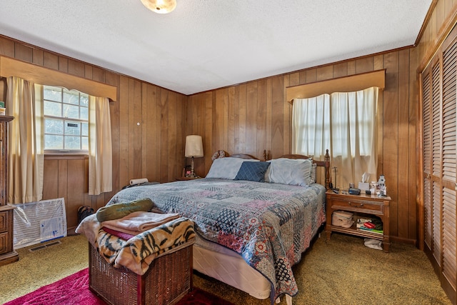 bedroom with carpet flooring, a textured ceiling, and wooden walls