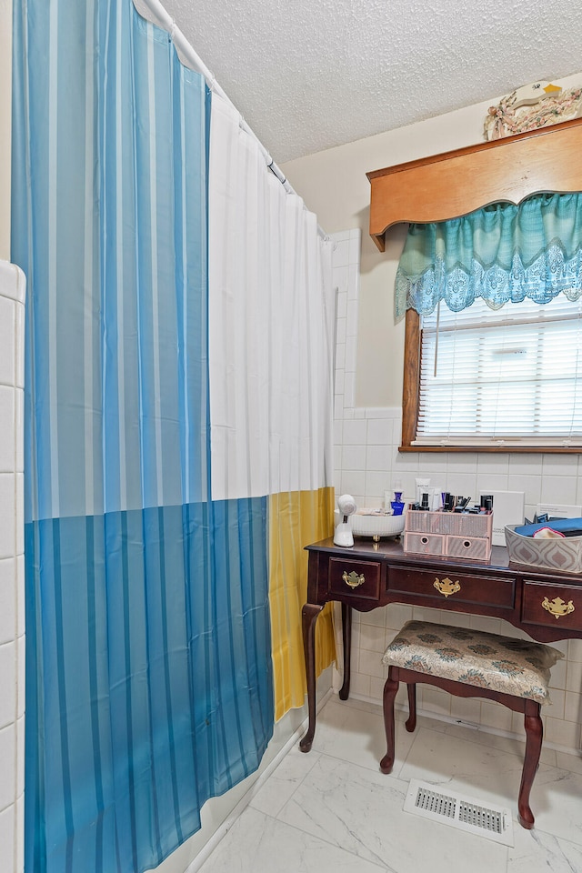 bathroom with walk in shower, tile walls, and a textured ceiling