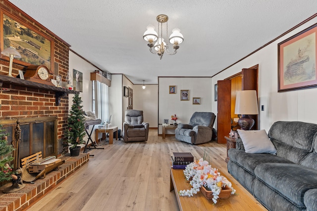 living room with light hardwood / wood-style floors, a textured ceiling, a fireplace, a chandelier, and crown molding