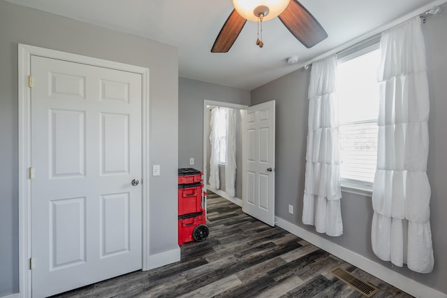 bedroom with multiple windows, dark hardwood / wood-style floors, and ceiling fan