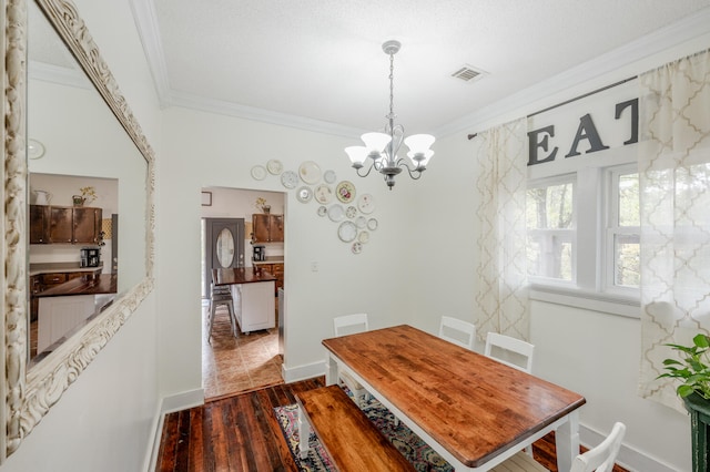 dining space featuring crown molding, dark hardwood / wood-style floors, and a chandelier