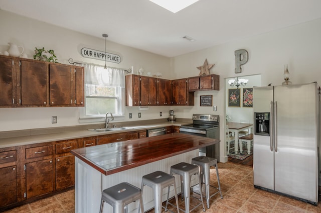 kitchen featuring a kitchen island, a breakfast bar area, stainless steel appliances, sink, and pendant lighting