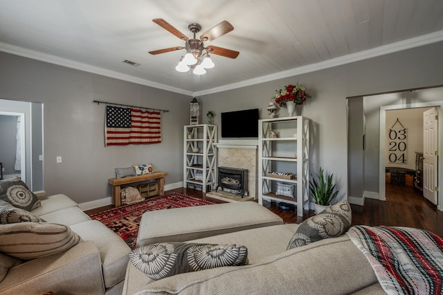 living room with crown molding, ceiling fan, a wood stove, and dark hardwood / wood-style flooring